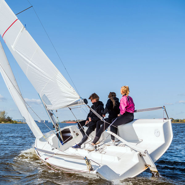 A fast, sporty, single-masted yacht with three athletes on board
